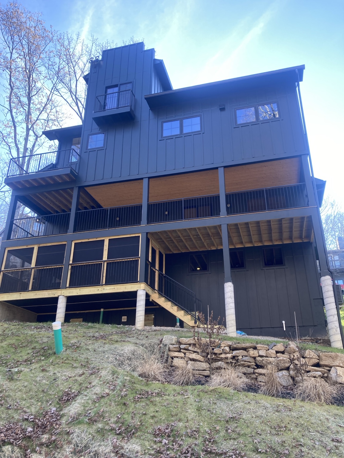 Rear elevation of a dark custom home with multiple decks