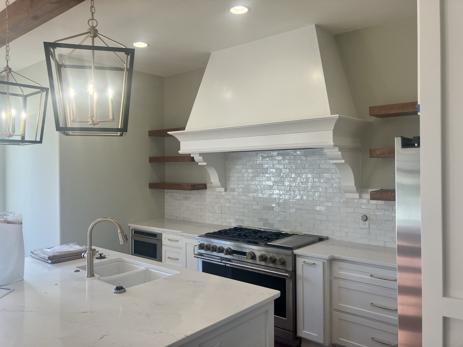 Custom kitchen hood, tile backsplash, cabinets, and floating shelves