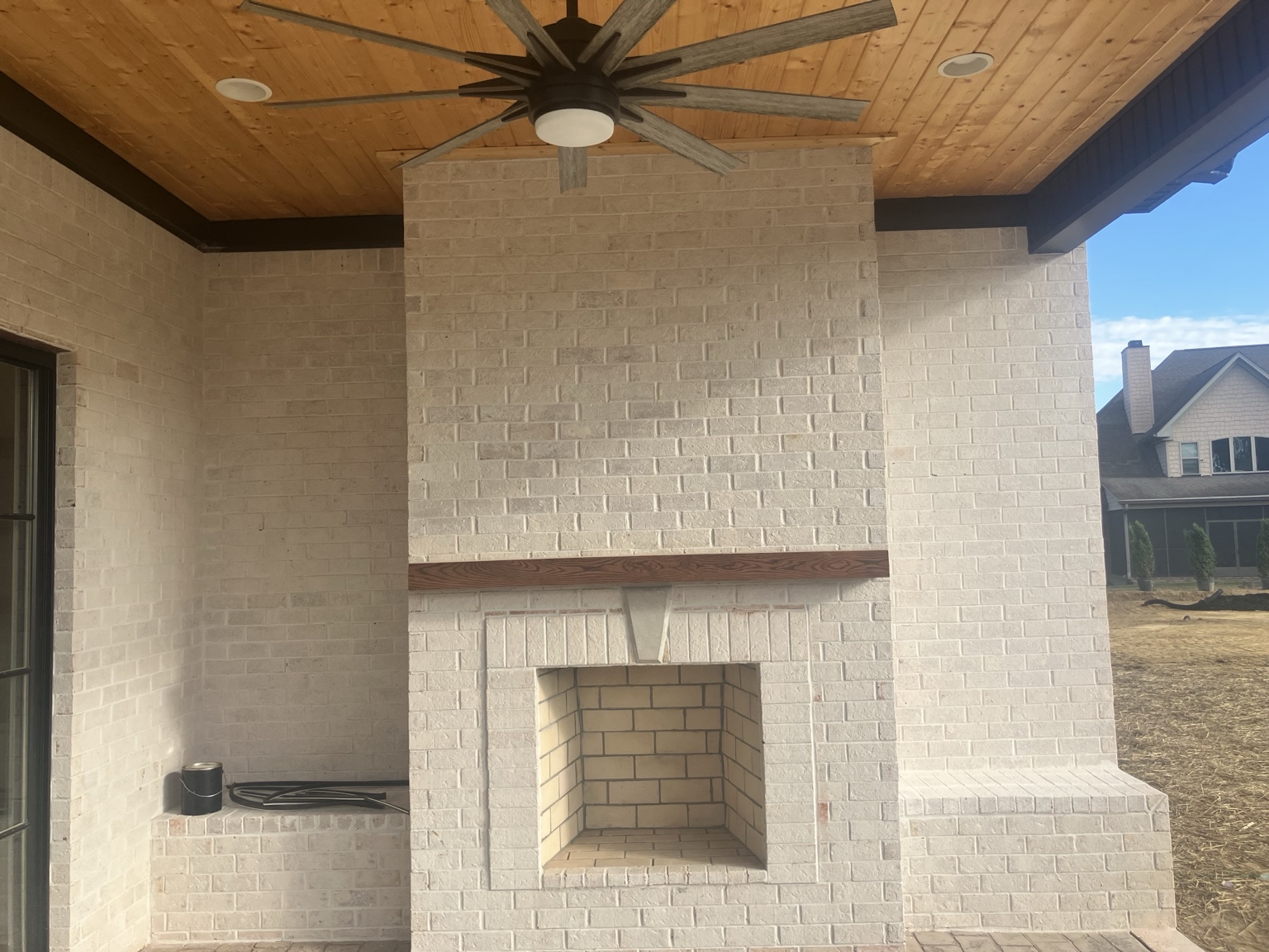 Finished covered outdoor living space with brick fireplace